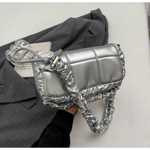 Détail d'un sac à main argenté matelassé avec bords à volants et bandoulière froncée