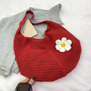 Détail d'un sac cabas tissé rouge avec une fleur en tricot 3D sur un fond en denim doux
