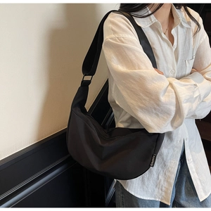 Vue détaillée du sac hobo en nylon noir avec bandoulière et étiquette de marque blanche