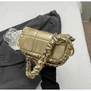Détail du sac à main matelassé or champagne avec bords à volants et fini métallique