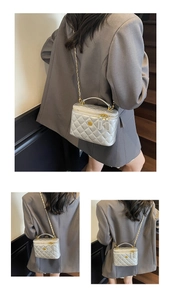Detail of silver quilted bucket bag with golden chain and camellia flower ornament