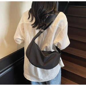Gros plan d'un sac bandoulière noir en forme de lune avec bandoulière réglable en tissu