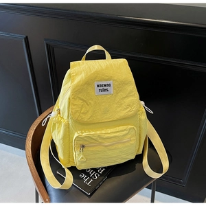 Detail of yellow nylon drawstring backpack with side pockets on a brown leather chair