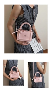 Dettaglio borsa in pelle verniciata rosa con logo stampato e ciondolo a fiocco carino