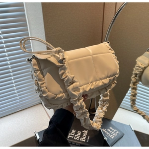 Vue détaillée du sac matelassé blanc crème avec des volants plissés et une texture douce
