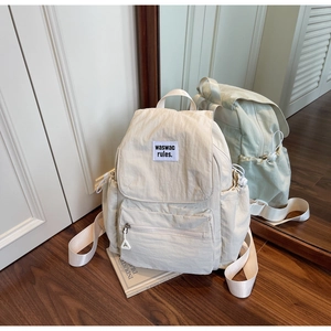 Detail view of beige nylon backpack with drawstring closure and waswac brand label