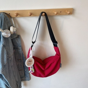 Vue détaillée d'un sac demi-lune rouge en nylon avec pendentif cartoon et bandoulière