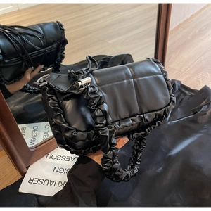 Détail d'un sac à main plissé noir avec texture matelassée à bulles et volants