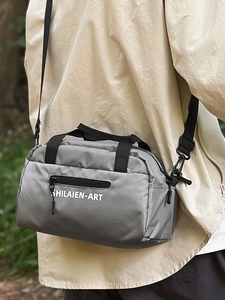 Gray waterproof athletic crossbody bag with letters shown in an outdoor lifestyle view