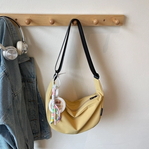 Détail d'un sac demi-lune jaune gingembre avec bandoulière et porte-clés décoratif