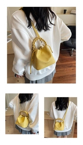 Detail view of yellow bucket bag with woven handle and lychee leather texture