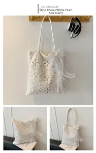 Dettaglio della borsa tote in pizzo bianco con motivi traforati e ciondolo a fiocco di perle