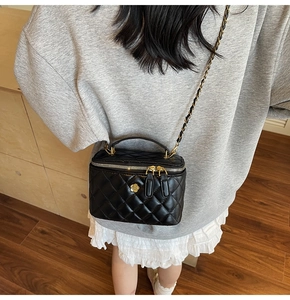 Detail of black quilted leather mini bag featuring gold camellia accent and chain strap