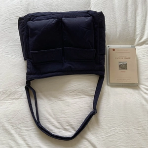 Detail of navy blue puffer canvas bag showing two front pockets and wide strap