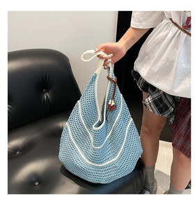 Detail of blue and white crochet bag featuring a cute 3D strawberry charm accessory