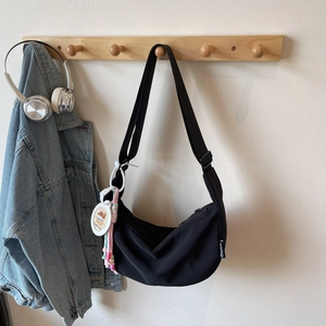 Détail du sac croissant en nylon noir avec étiquette tissée et breloque arc-en-ciel colorée