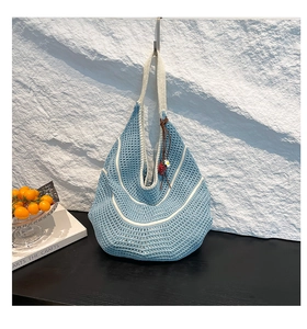 Close-up of contrast color hollow knit tote bag with strawberry charm hanging on hook