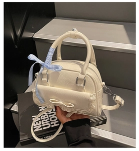 Detail der cremeweißen Schleifenhandtasche mit Faltenleder und Spitzenbesatz