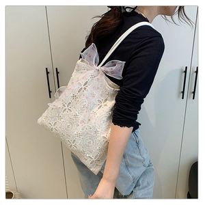 Dettaglio di borsa tote in pizzo bianco con fiocco decorativo in organza a ciliegie rosa