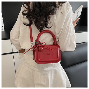 Dettaglio della borsa mini rossa in PU lucido con logo goffrato e ciondolo a fiocco chic
