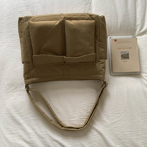 Flat lay of khaki canvas messenger bag with dual front pockets and shoulder strap