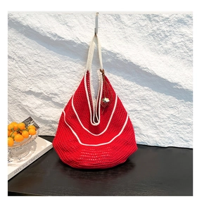 Detailed close-up of handmade red crochet tote bag with white stripes and strawberry charm