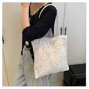 Dettaglio della borsa tote in pizzo floreale bianco con ricami e nastro di seta rosa decorativo