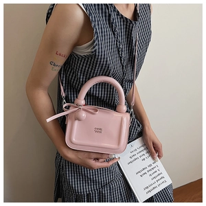 Borsa a mano in pelle verniciata rosa con scritte a rilievo e ciondolo a fiocco