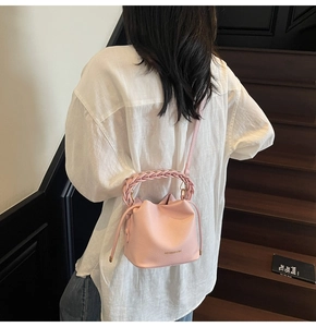 Detail of pink bucket bag with woven handle and drawstring closure on stairs