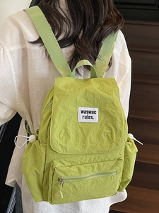 Light green drawstring backpack with flap and woven label shown on a model