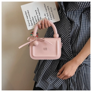 Dettaglio mini borsa in pelle verniciata rosa chiaro con lettere sbalzate e fiocco