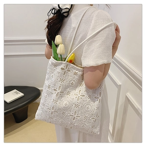Dettaglio della borsa tote in pizzo bianco con ricami floreali e design traforato chic