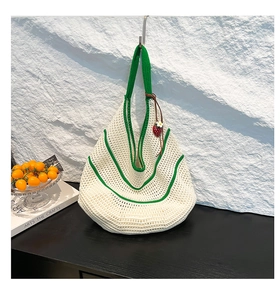 Detailed knit texture of white and green crochet shoulder bag with a strawberry charm