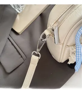 Makroansicht von Silberreißverschluss und Beschlägen an cremefarbener Tasche mit Schleife