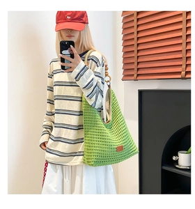 Detail of green knit hobo bag with wooden bead strap accents and hollow grid texture