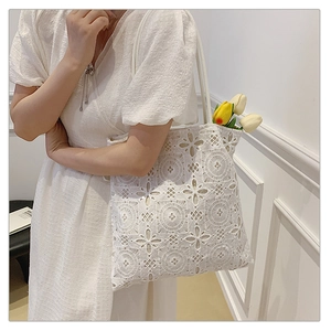Dettaglio della borsa tote in pizzo bianco con motivi floreali traforati e cotone