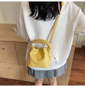 Rear view of model wearing a bright yellow litchi grain leather bucket bag with braided handle
