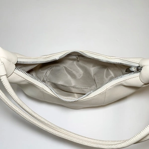 Detail view of cream shoulder bag with chevron lining and internal zipper pocket