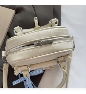 Nahaufnahme des silbernen Reißverschlusses und der blauen Schleife an der Ledertasche
