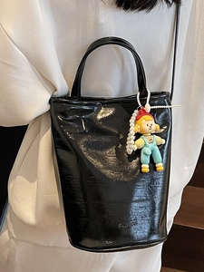 Sac seau chic en cuir verni noir avec poignée supérieure et breloque poupée arc-en-ciel