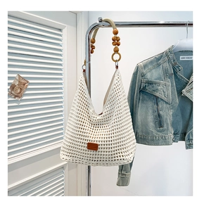 Detail of white crochet shoulder bag featuring unique wooden bead strap and leather patch