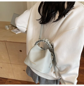 Detail of light grey bucket bag with woven handle shown in a modern home lifestyle setting