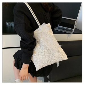 Dettaglio della borsa tote in pizzo bianco con ricami floreali e fiocco con perle