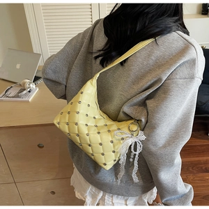 Detail of yellow quilted shoulder bag with silver studs and lace bow pearl charm