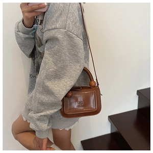 Dettaglio mini borsa marrone vintage in pelle PU con manico a sfera e tracolla sottile