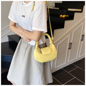 Detail of light yellow crescent bag featuring unique round wooden bead handle accents