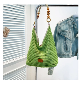 Detail of green handmade crochet tote bag featuring wooden beads and mesh texture