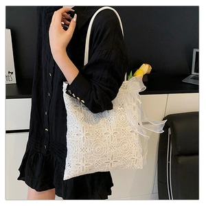 Dettaglio della borsa tote in pizzo bianco con fiocco in rete e ciondolo di perle ornato