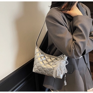 Detail of silver quilted underarm bag with lace bow and pearl charm on a model