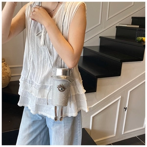 Detail of silver glitter cylinder crossbody bag with crystal eye motif and doll leg charms